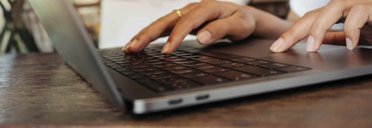 Manos escribiendo en el teclado de una computadora portátil