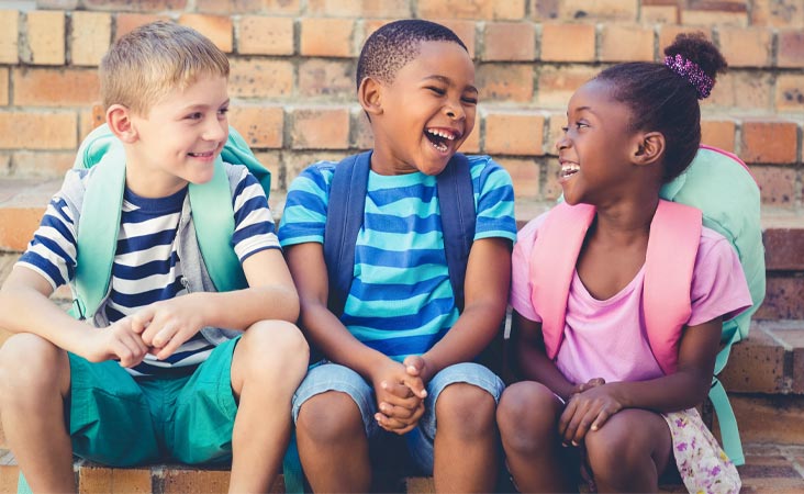 Un grupo de niños que están sentados y sonríen