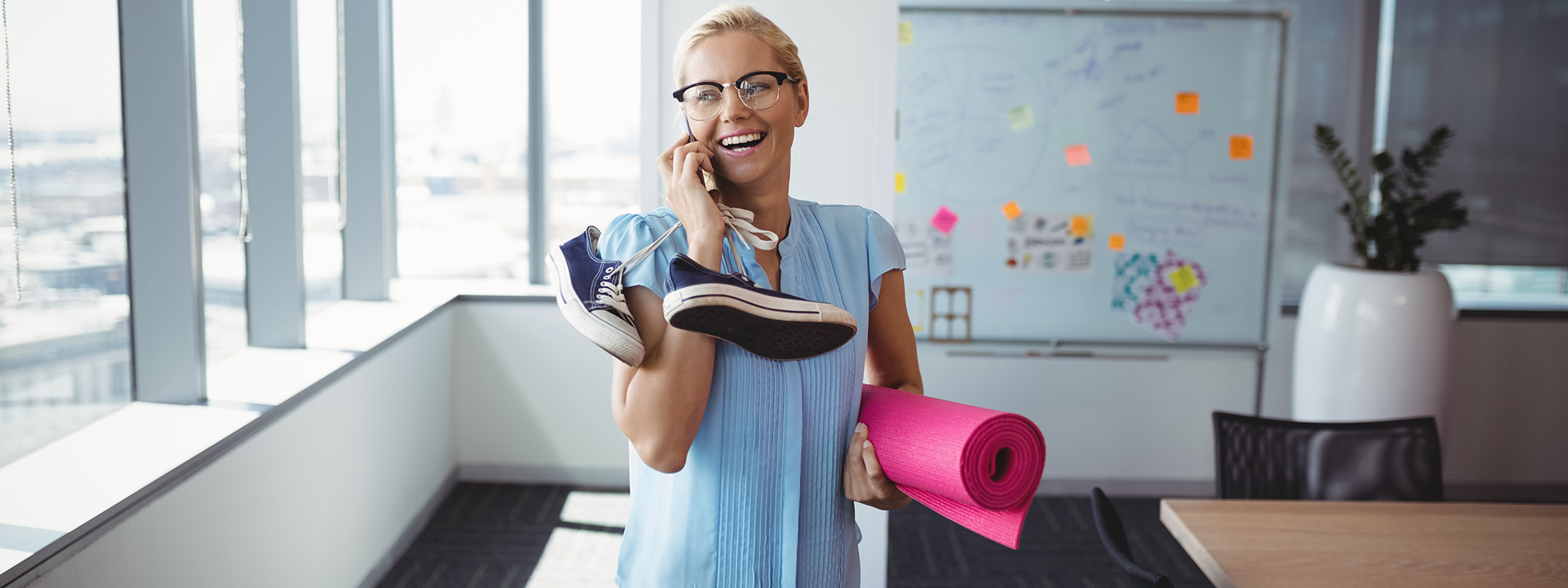 smiling-woman-holding-yoga-mat-shoes_1900x713