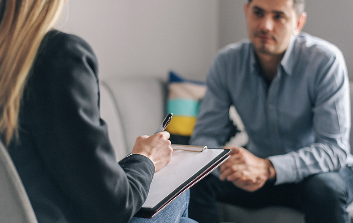 Therapist listening to patient while writing on clipboard