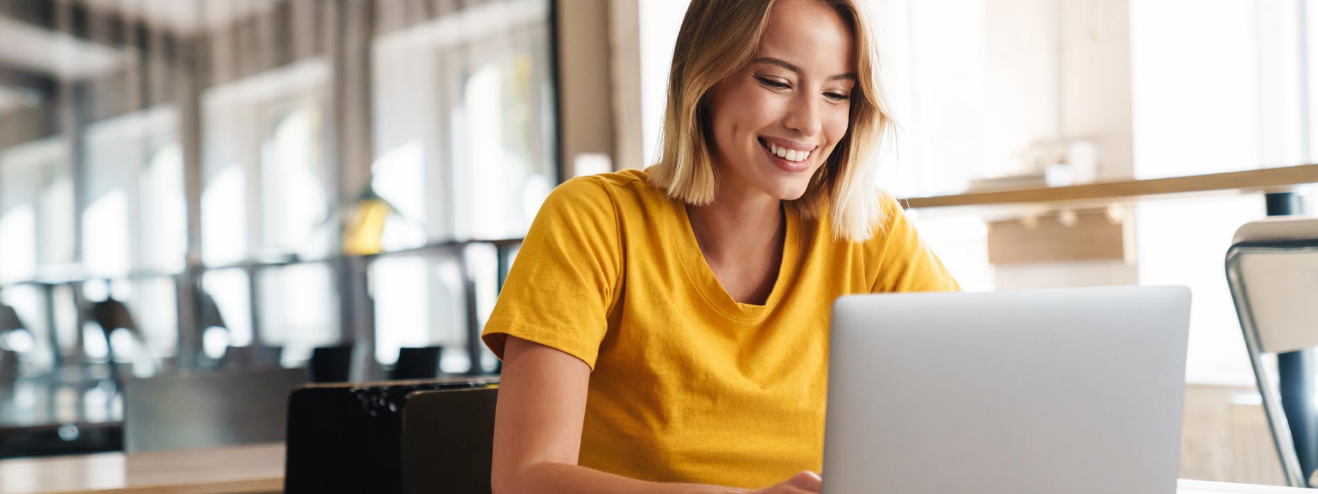 Woman-sitting-and-smiling-at-laptop-screen