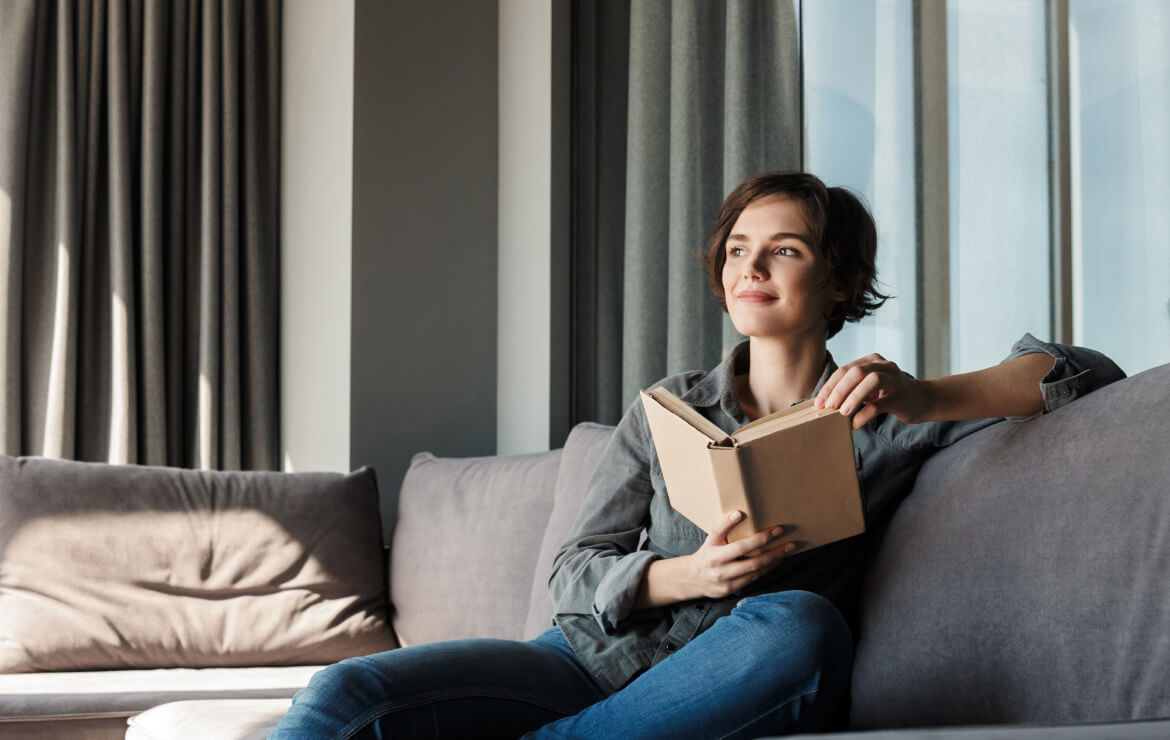 Woman sitting on couch holding a book