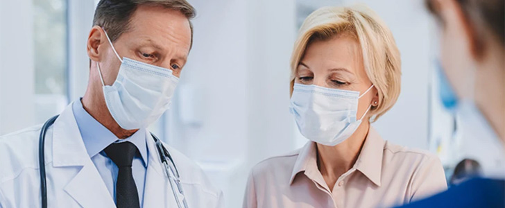 Doctor and patient wearing masks reviewing exam notes together