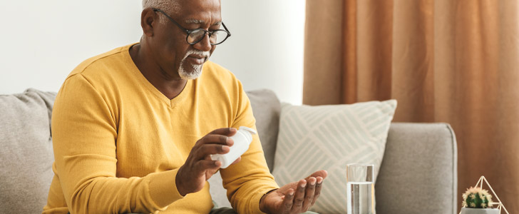 Man sitting on couch pouring prescription bottle out