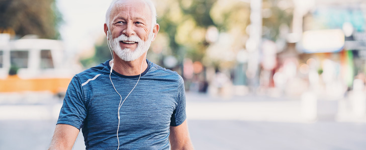 Older man wearing earbuds walking outside