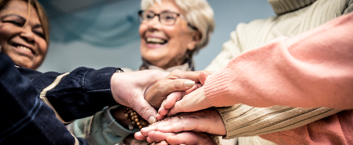 Group of woman putting hands together to celebrate Breast Cancer Awareness month