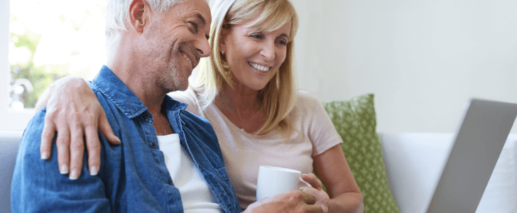 Older couple smiling while looking at laptop