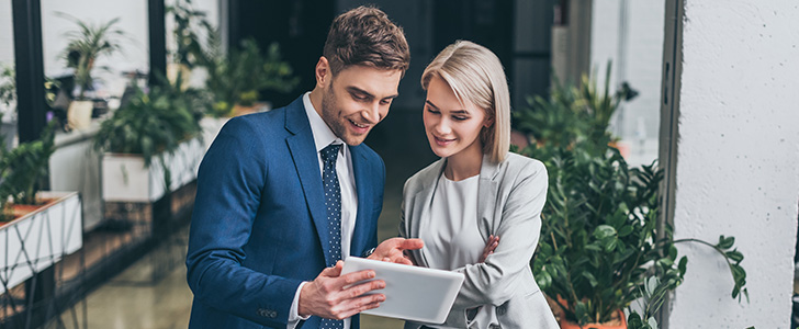 Smiling businessman and businesswoman viewing tablet