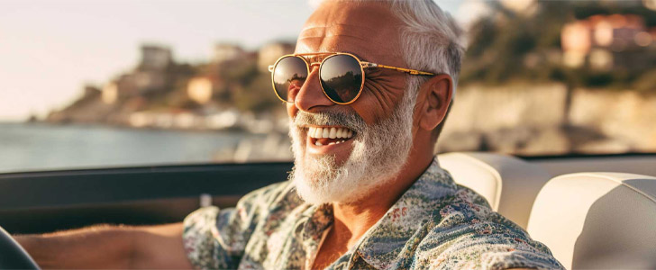 Older man smiling while driving a car on vacation