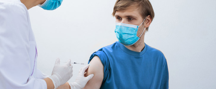 Doctor giving patient flu shot vaccine while wearing mask